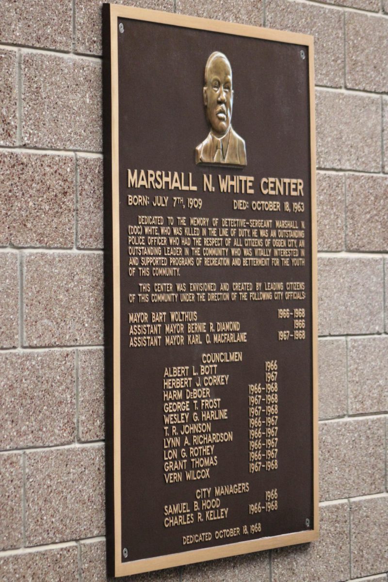 A plaque inside of the Marshall White Center, dedicating the building in honor of his memory.// Una placa dentro del centro Marshall White, dedicando el edificio en honor a su memoria.