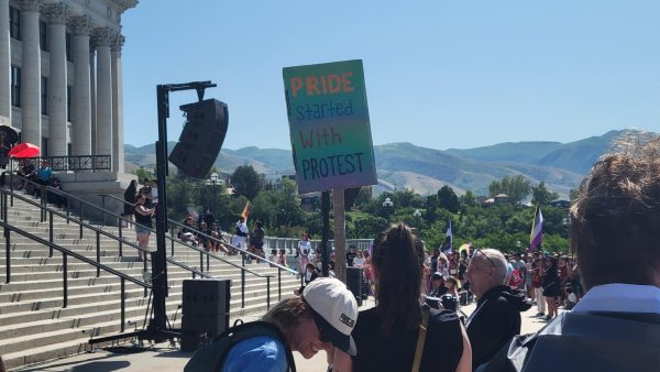 A protest sign is held up at the Pride Rally reading, "Pride started with protest."// Un letrero de la protesta del rally de Orgullo dice, "El orgullo empezo con una protesta"