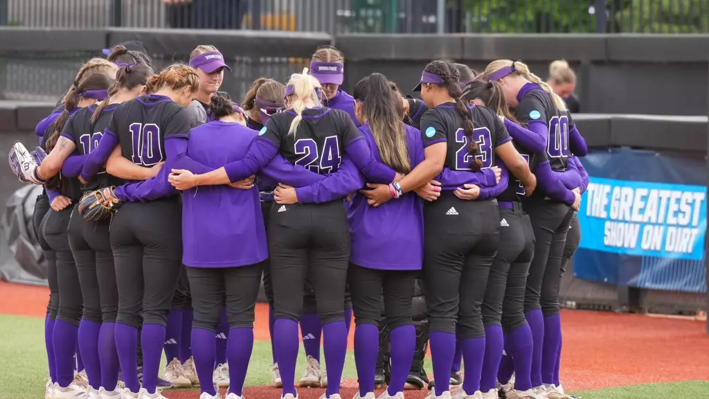 Weber State softball huddling together in the NCAA tournament game.// El equipo de softball de Weber State agrupándose en el juego del torneo de NCAA.