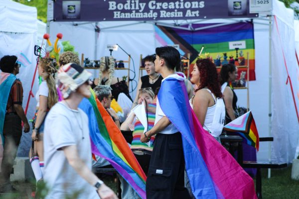 People wearing pride flags walking through the Pride Festival. (Anna Kuglar/The Signpost)// Personas usando como vestimenta la bandera de Orgullo mientras caminan por el Festival de Orgullo.