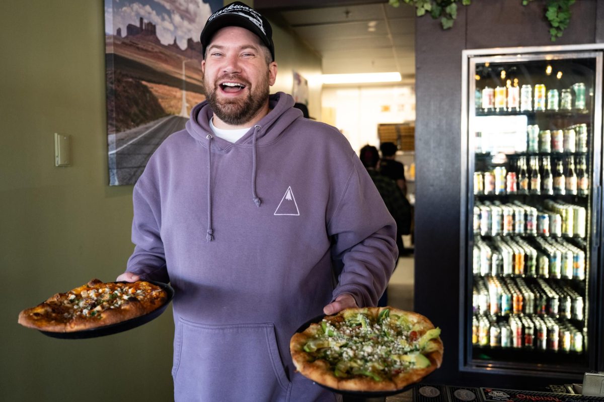 Griffin Delozier, the manager at Slackwater, delivering pizzas from the kitchen to customers. // Griffin Delozier, gerente de Slackwater, repartiendo pizzas desde la cocina a los clientes.