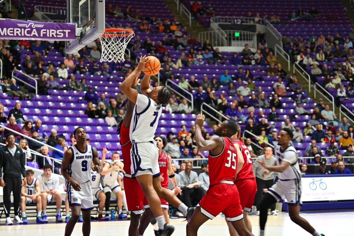Weber State University forward and center Malek Gomma (#7) attacks the basket in traffic, rising for a close‑range shot against multiple Eastern Washington University defenders as the crowd watches intently on Jan. 15, 2026.