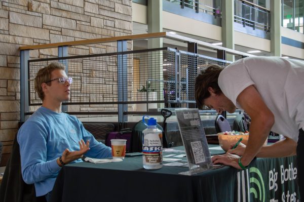 Quin Ence (left) offers an overview of Big Brothers Big Sisters, while Carl Grimm (right) records his contact details as an interested Mentor during the Career Fair. // Quin Ence (izquierda) ofrece una visión general de Big Brothers Big Sisters, mientras que Carl Grimm (derecha) anota sus datos de contacto como mentor interesado durante la feria de empleo.