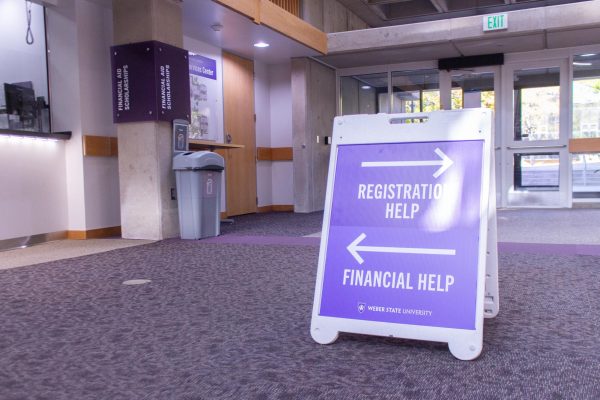 A sign near the entrance of the Student Services building points visitors to the location of the Financial Aid office and Registration services.

Un letrero por la entrada del edificio de servicios estudiantiles que señala la ubicación del oficio de apoyo financiero y los servicios de registración.