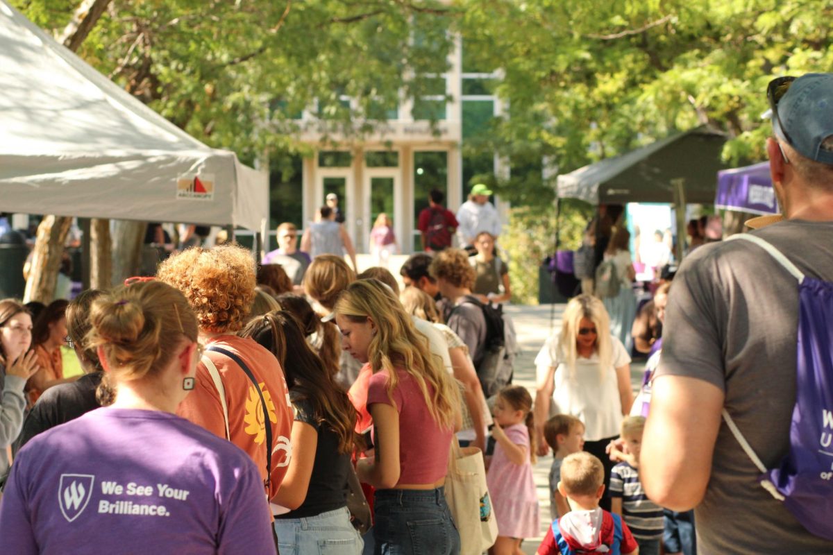 Students look at different Block Party booths.// Estudiantes observan a diferentes cabinas del Block Party.