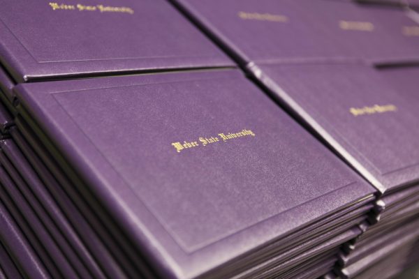 A stack of Weber State University diploma covers for graduation. /Una pila de fundas para diplomas de la Universidad de Weber State para la graduación.